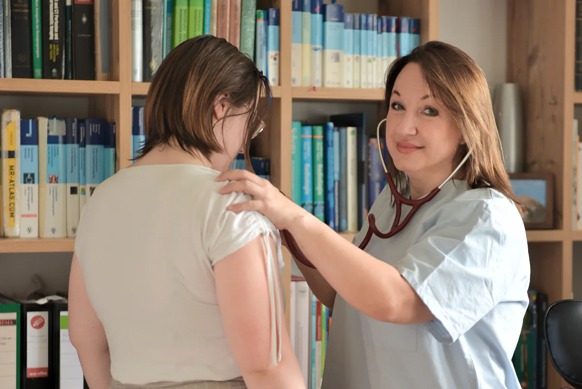 Arbeitsmedizinerin Dr. Jessica Vollmann hört eine Mitarbeiterin mit Stethoskop ab – betriebsärztliche Untersuchung vor Ort in Wien.